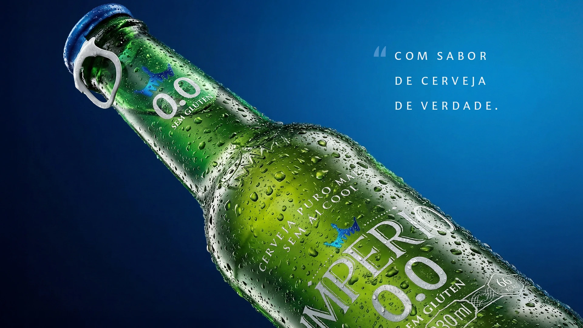 Close diagonal da garrafa verde Império 0.0 coberta de gotas, em fundo azul, com o texto "Com sabor de cerveja de verdade."